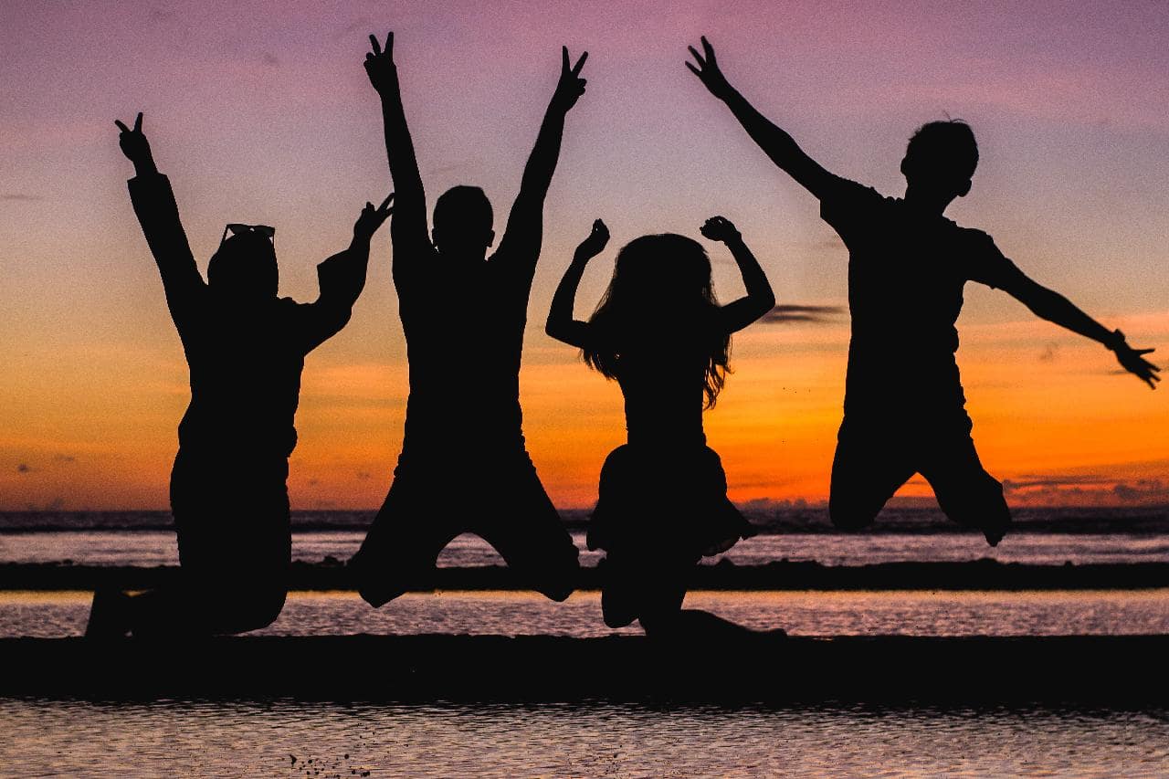 People jumping near the beach in the evening.