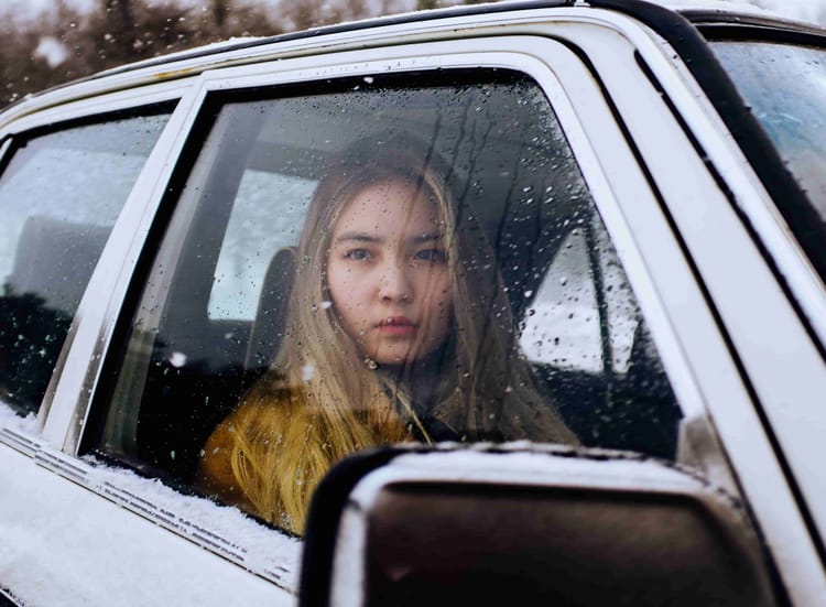 Woman in car in cold weather. In a crisis, emergency sleeping bags can keep you warm.