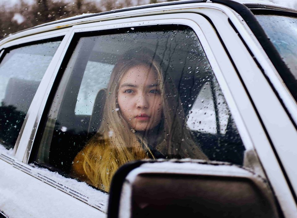 Woman in car in cold weather. In a crisis, emergency sleeping bags can keep you warm.